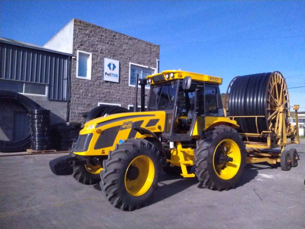 Tractor con rollo de tubería de polietileno para tendido de riego en el campo
